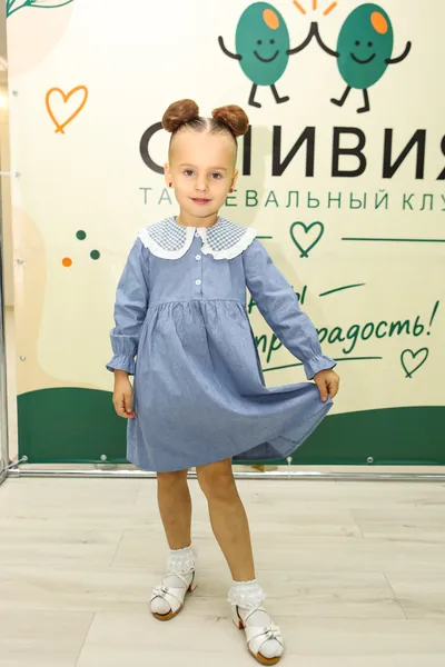 Юная ученица улыбается на фоне фирменного баннера клуба